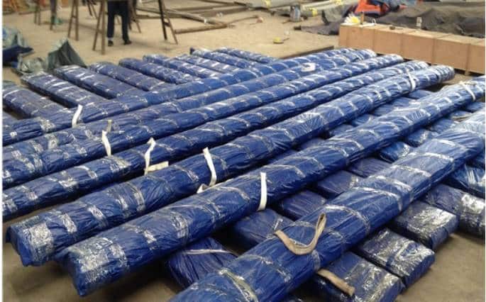 neatly stacked and securely packaged metal rods or steel bars wrapped in blue plastic, ready for transport or delivery in an industrial setting
