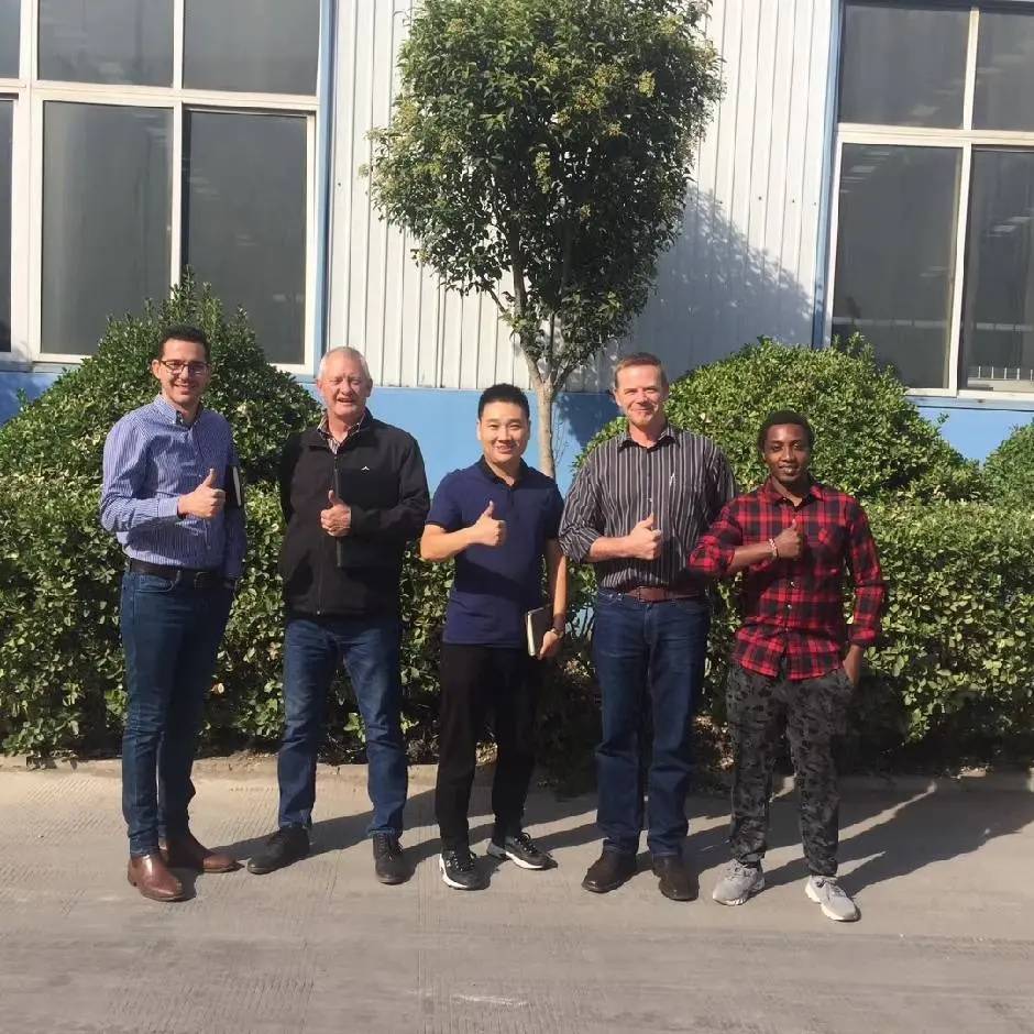 Five men standing together outside a factory building giving a thumbs-up after a successful supplier visit