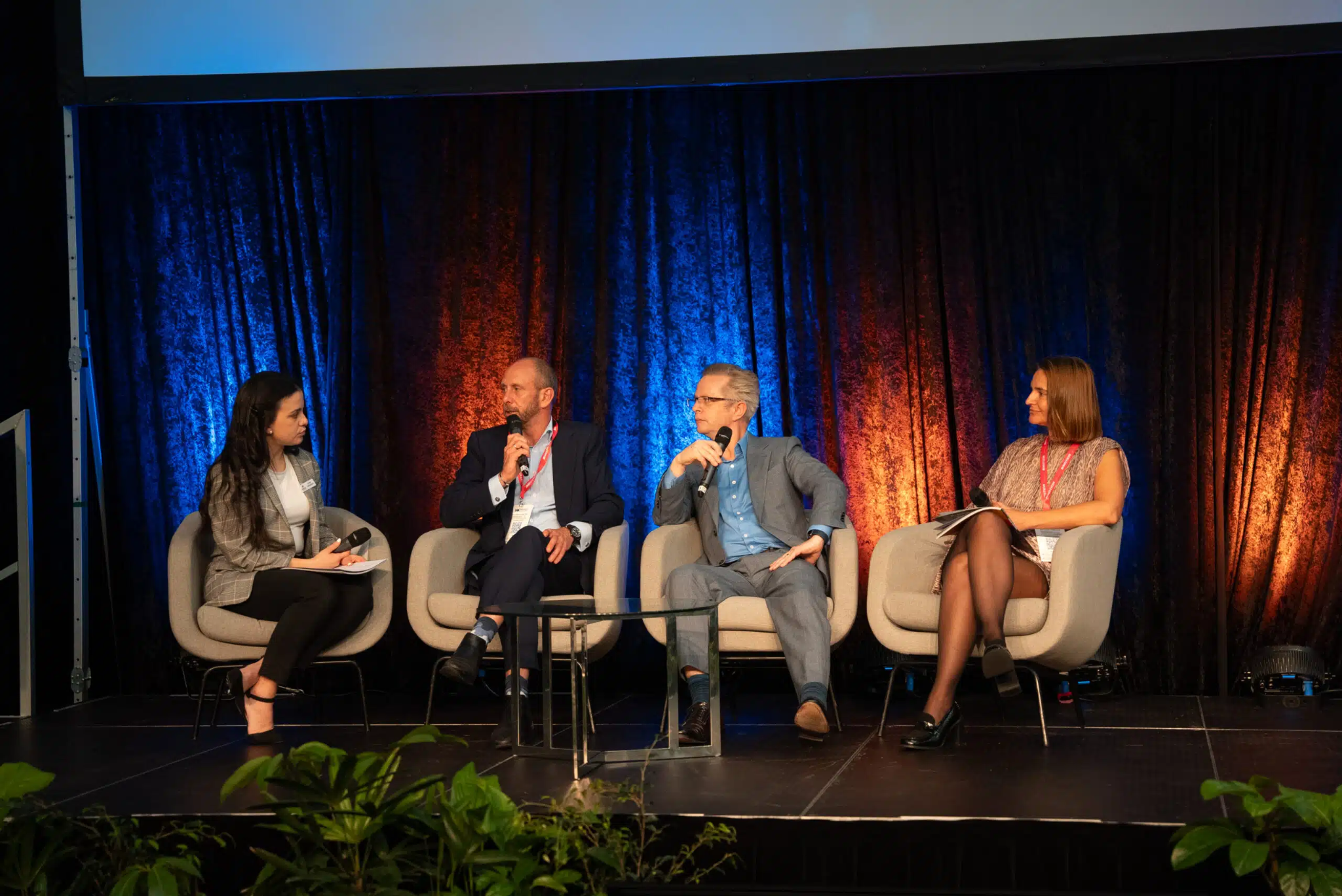 Four panelists seated on stage under blue and orange stage lighting during a WA Mining conference panel discussion, each holding a microphone